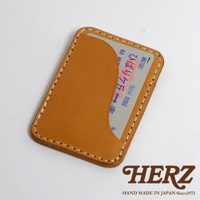 職人手作皮革名片收納夾，淺棕色皮革，縫線精緻，內插一張日文卡片，右下角有HERZ品牌標誌。