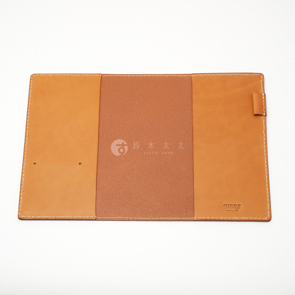 職人手作皮革B6記事本書套，淺棕色皮革，內層為較深棕色皮革，側邊有縫線裝飾，右側有筆插，內頁中央印有品牌標誌。