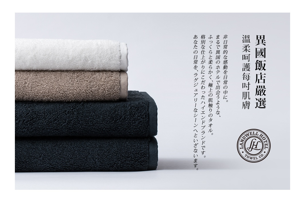 疊放的泉州匹馬棉浴巾，由上至下分別為白色、淺棕色和深藍色，質地柔軟，帶有品牌標誌。