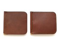 兩件棕色皮革製的橫式對折短夾，以咖啡色縫線裝飾，一側帶有金色金屬夾。