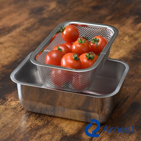 不鏽鋼濾網裡裝著新鮮的番茄，下方疊著一個不鏽鋼調理盤，盤底有Arnest的品牌標誌。