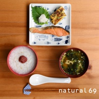 裝有烤鮭魚、玉子燒、蘿蔔泥和紫蘇葉的白色方形餐盤，盤面印有藍色魚圖案。旁邊是裝有飯的紅色碗和味噌湯的深紅色碗，以及白色湯匙和木筷。