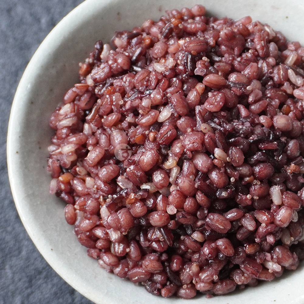 一碗裝滿深紅色十六穀米的特寫鏡頭，穀物飽滿、顆粒分明，部分帶有光澤。
