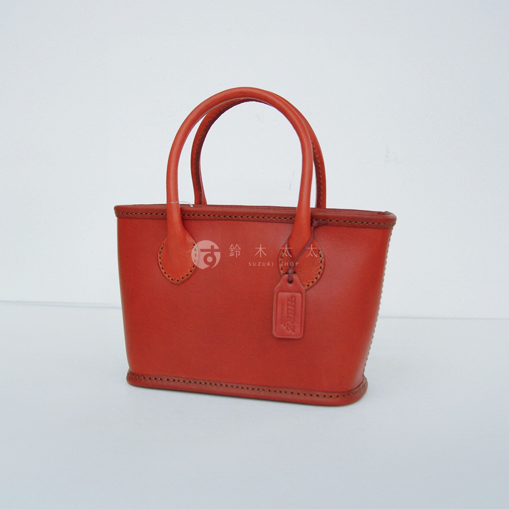 紅色皮革手提包，方形設計，配有兩個短提把，包身側面有縫線裝飾，並懸掛一個皮革吊牌。