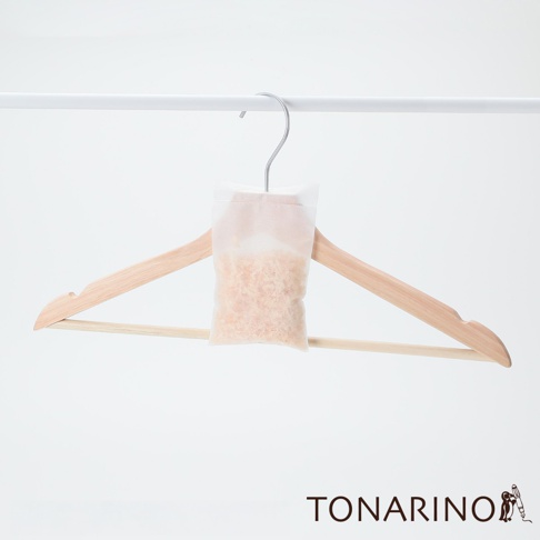 純天然防潮消臭檜木除濕包 M，裝有淺棕色檜木碎屑，懸掛於淺木色衣架上，衣架掛在白色掛桿上。