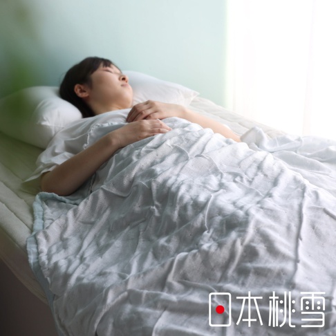 一位女子蓋著淺藍色二層紗半毯，毯子表面有細緻的紋理，呈現輕柔的質感。