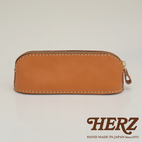 職人手作皮革三角弧形收納筆袋，採用紮實的皮革材質，咖啡棕色，搭配質感金色拉鍊，整體呈現簡約實用的設計風格。