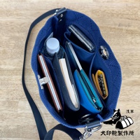 深藍色刺子織迷你側背包，內部整齊擺放著手機、錢包、筆記本、水瓶及鑰匙包，材質為紋理感的織布，搭配銀色金屬釦。