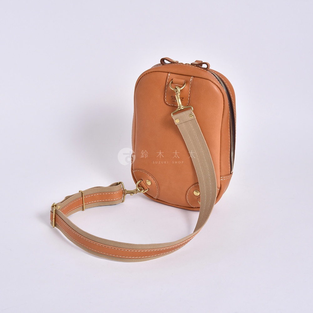日本HERZ品牌橘棕色Stare皮革立體運動斜背包，配有可拆卸與調整的帆布及皮革製成的肩背帶，整體呈現簡約俐落的職人手作風格。