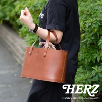 棕色皮革束口手提包，有兩個提把，包身方形，邊緣縫線明顯，包內有束繩。