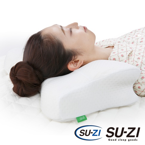 白色記憶棉止鼾枕，具有人體工學設計，中央凹陷，兩側隆起，能支撐頭頸。枕套表面有細微的菱形紋理，右下角有綠色SU-ZI品牌標籤。