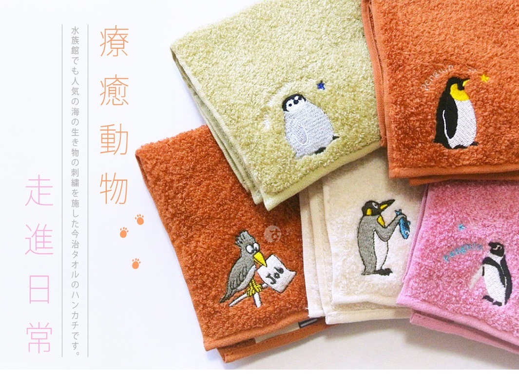 多條毛巾疊放，顏色包含淺綠、橘紅、米白和粉紅，每條毛巾上繡有可愛的企鵝或鳥類圖案，材質為絨毛。