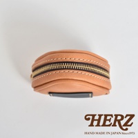 淺棕色皮革製成、飯糰造型的職人手作小物收納包，配有金色拉鍊及黑色皮革裝飾，縫線清晰可見。