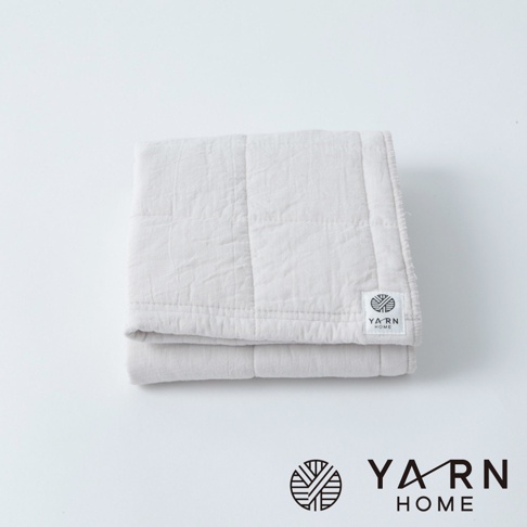 淺米色格紋毛巾，材質為脫脂棉混紗，表面有縫線紋路，右下角有品牌標籤。