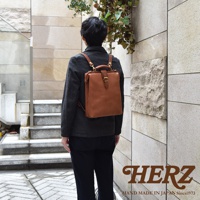 職人手作皮革軟式杜勒斯包，焦糖色皮革，方形包身，配有金屬扣環和提把，可轉換為後背包，展現經典復古風格。