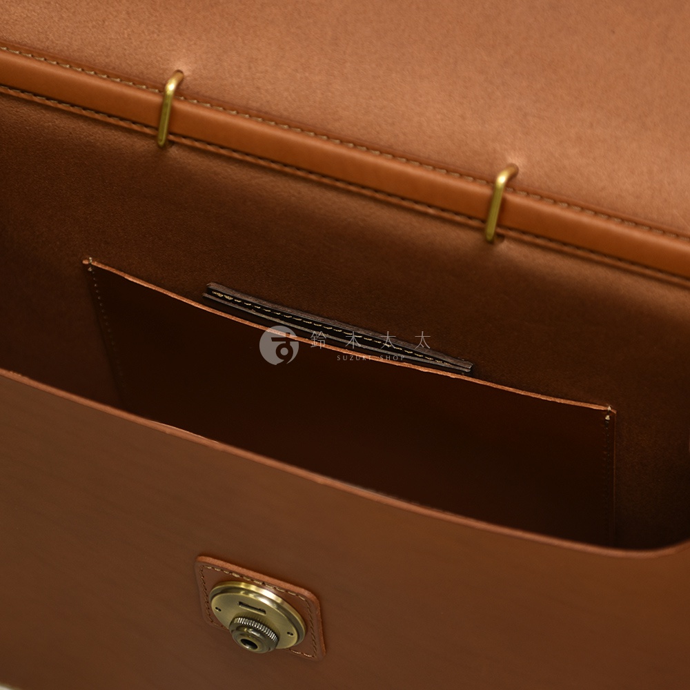職人手作皮革Organ兩用商務公事包 G-93，內部特寫，展示棕褐色皮革材質，包含一個內袋和一個金屬旋轉鎖扣，以及品牌標誌。