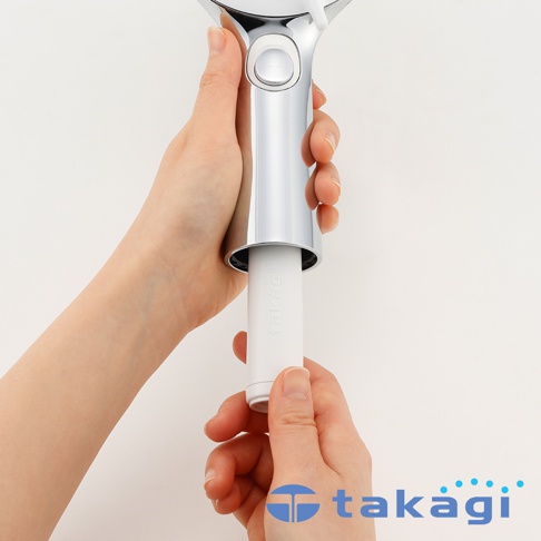 一雙手正將一個印有 takagi 字樣的白色圓柱狀除氯濾芯，安裝進金屬質感的蓮蓬頭握把中，呈現出產品替換濾心的操作過程。