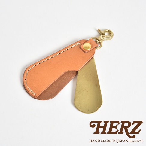 職人手作皮革隨身金屬鞋拔，採用天然皮革與黃銅材質，皮革部分為淺棕色，金屬部分為黃銅色，搭配金色鉤扣，適合隨身攜帶。