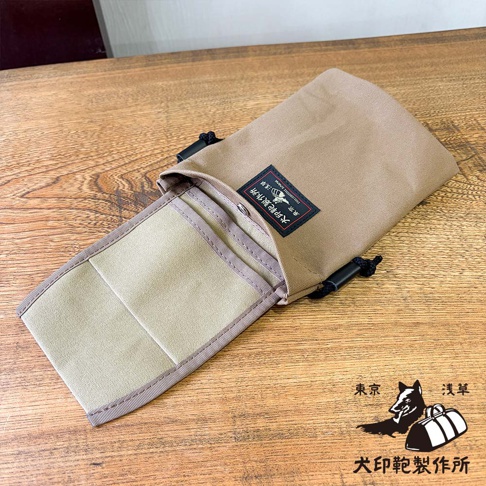 犬印鞄製作所純綿帆布手機包，採用卡其色設計，帶有黑色束繩和品牌標籤。