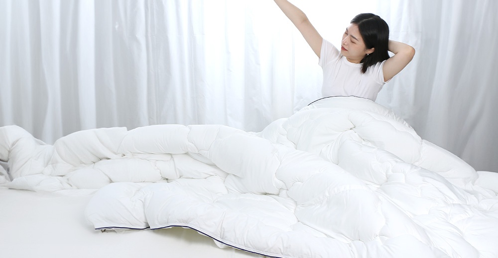 一個女人躺在床上，伸展身體，背景是白色窗簾。