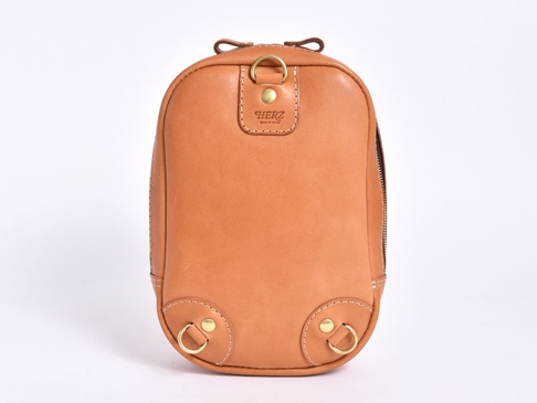 職人手作皮革立體運動斜背包，採用天然棕色皮革製成，包身呈現圓潤立體造型。包面有壓印品牌標誌，頂部和底部設有金屬D型環，搭配拉鍊開合。