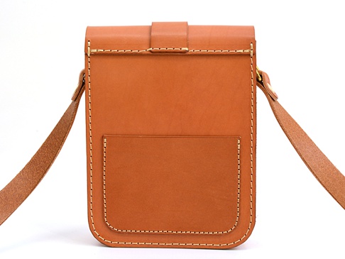 棕色皮革製作的單肩包，有經典皮扣和外接小口袋，邊緣縫線明顯，附有皮革肩帶。
