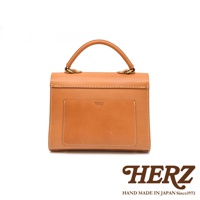 HERZ 焦糖色皮革手提包，正面設有品牌壓印和一個置物袋，搭配金色五金提把。