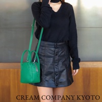 鮮綠色皮革手提包，帶有雙提把和可拆卸斜揹帶，包身為貝殼狀，飾有銀色拉鍊。