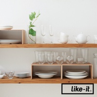 木紋雙層整理架，上方擺放著玻璃杯、白色茶壺與疊放的白色杯子，下方則有木紋隔板，隔板上放置白色盤子與玻璃杯。