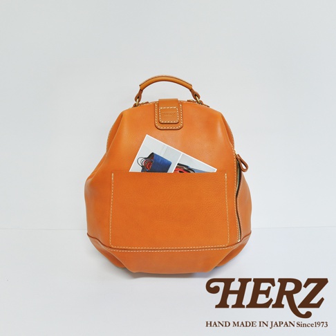 職人手作皮革輕旅行後背包 R-144，焦糖色皮革，簡約設計，前方有外袋，內有雜誌展示。