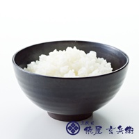 黑色陶瓷碗中盛有飽滿的白色米飯，碗底有深色材質，碗邊緣有細微紋理。