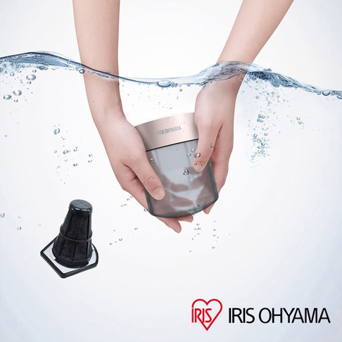 雙手捧著銀灰色帶金屬頂蓋的圓柱形清淨機，上方有水流和氣泡，左側有一個黑色圓錐形濾網。