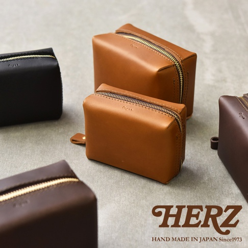 HERZ 品牌標誌，下方印有 HAND MADE IN JAPAN Since1973 字樣，旁邊展示了數個不同顏色和尺寸的皮革收納包。