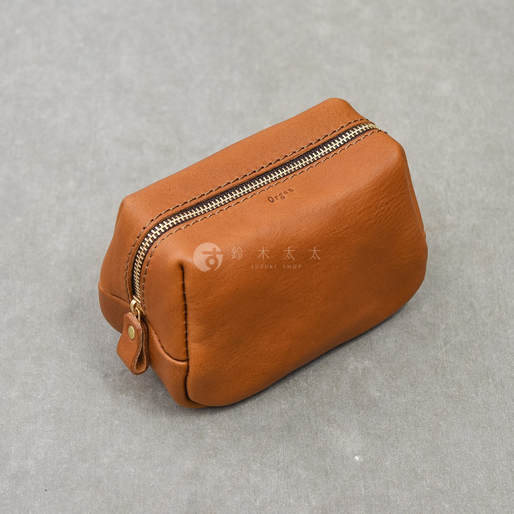 一個置於灰色背景上的日本HERZ職人手作Organ皮革拉鍊收納包，呈現長方形結構，採用暖棕色柔軟皮革製成，頂部設有金色金屬拉鍊，皮革表面壓印有Organ字樣，整體展現簡約質樸的工藝質感。
