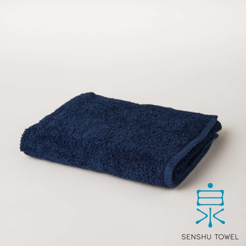 深藍色SOLID迷你浴巾，觸感細緻，材質蓬鬆，表面帶有緞澤光澤，邊緣有縫線。