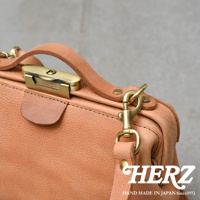 日本HERZ職人手作皮革Organ鎖孔式大開口肩背包M-7，淺褐色牛革材質，金屬鎖扣與掛鉤細節，特寫鏡頭。