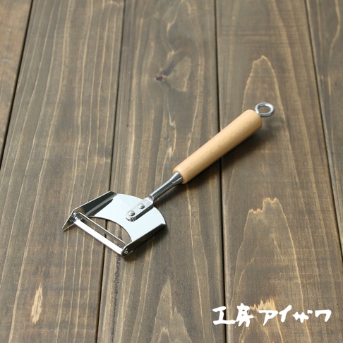 VEGET 不鏽鋼木柄削皮刀，配有銀色不鏽鋼刀刃和銀色連接件，以及一個圓柱形淺木色木柄，末端帶有一個金屬掛環。