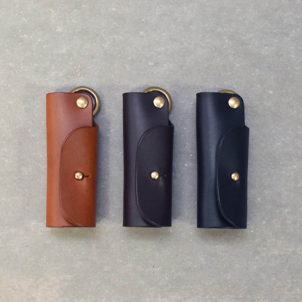 三款職人手作皮革鑰匙套，分別為棕色、深咖啡色及黑色，皆採用真皮材質，設計簡約，配有黃銅色金屬扣環及按鈕，可收納鑰匙。