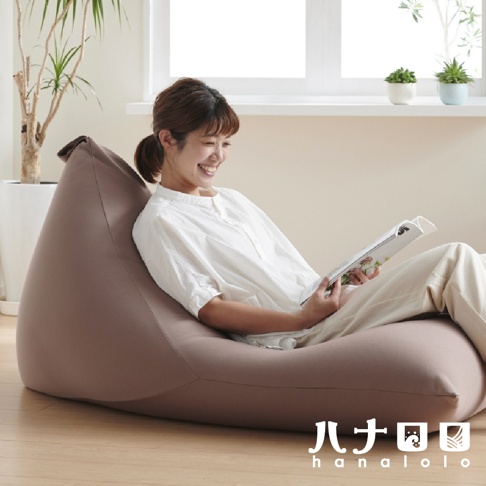 一位女性坐在粉色針織布款懶骨頭沙發上，手持雜誌閱讀。