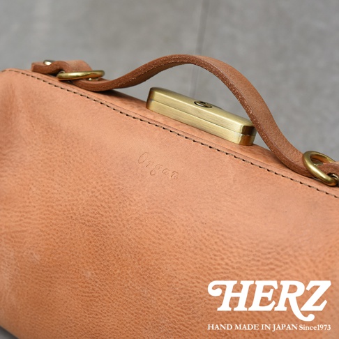 HERZ 品牌皮革包，上面有 Organ 的壓印字樣，並有一個鎖孔式金屬扣。