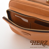 駝色皮革製成的兩用商務公事包，拉鍊部分打開，露出內部有卡槽及隔層。包身上有壓印品牌標誌。