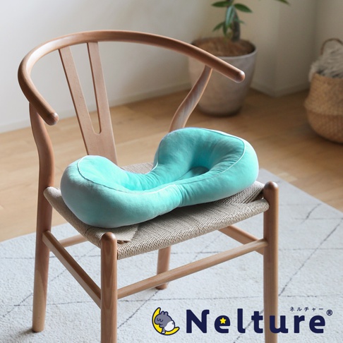 一塊土耳其藍色的瑜珈感舒壓美姿矯正坐墊，放在木椅上，品牌 Nelture 的 Logo 標誌在右下方。