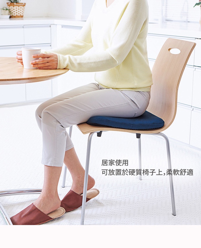 藍色蜂巢式冷凝膠坐墊，帶有網眼布套，放置於淺色木質椅子上，由一位穿著淺黃色毛衣和米色褲子的女性使用。