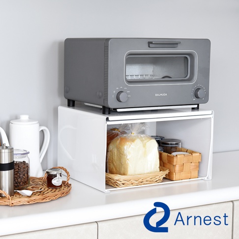 灰色的多功能小烤箱，下方為白色兩層收納架，架上擺放著一條麵包、小籃子和罐子。