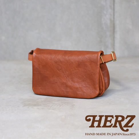 職人手作皮革Organ斜背包，採用柔軟的棕色皮革製成，包身呈現自然的皺褶感，並配有可調節的皮帶和金色金屬扣環。