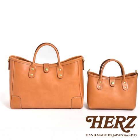 一對淺棕色職人手作皮革迷你托特包，以簡約的設計和精緻的縫線展現皮革質感。