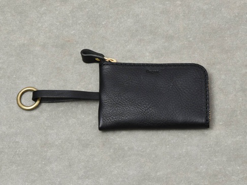 黑色皮革鑰匙包，附有金色拉鍊、皮革拉環和金色掛環，包身呈現粒面紋理。