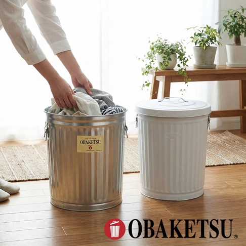 模式B： 一個人將衣物放入左側的金屬垃圾桶，右側有一個白色帶蓋的垃圾桶，上方擺放著盆栽植物。