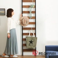 頂天立地收納掛架，黑色金屬框架，裝有橫向木紋層板，可掛置淺褐色圓頂帽和軍綠色帆布袋。