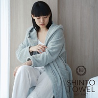 一位女性穿著一件淺藍色的連帽蓬鬆浴袍，搭配白色長褲。浴袍材質看起來柔軟，有著明顯的織紋。